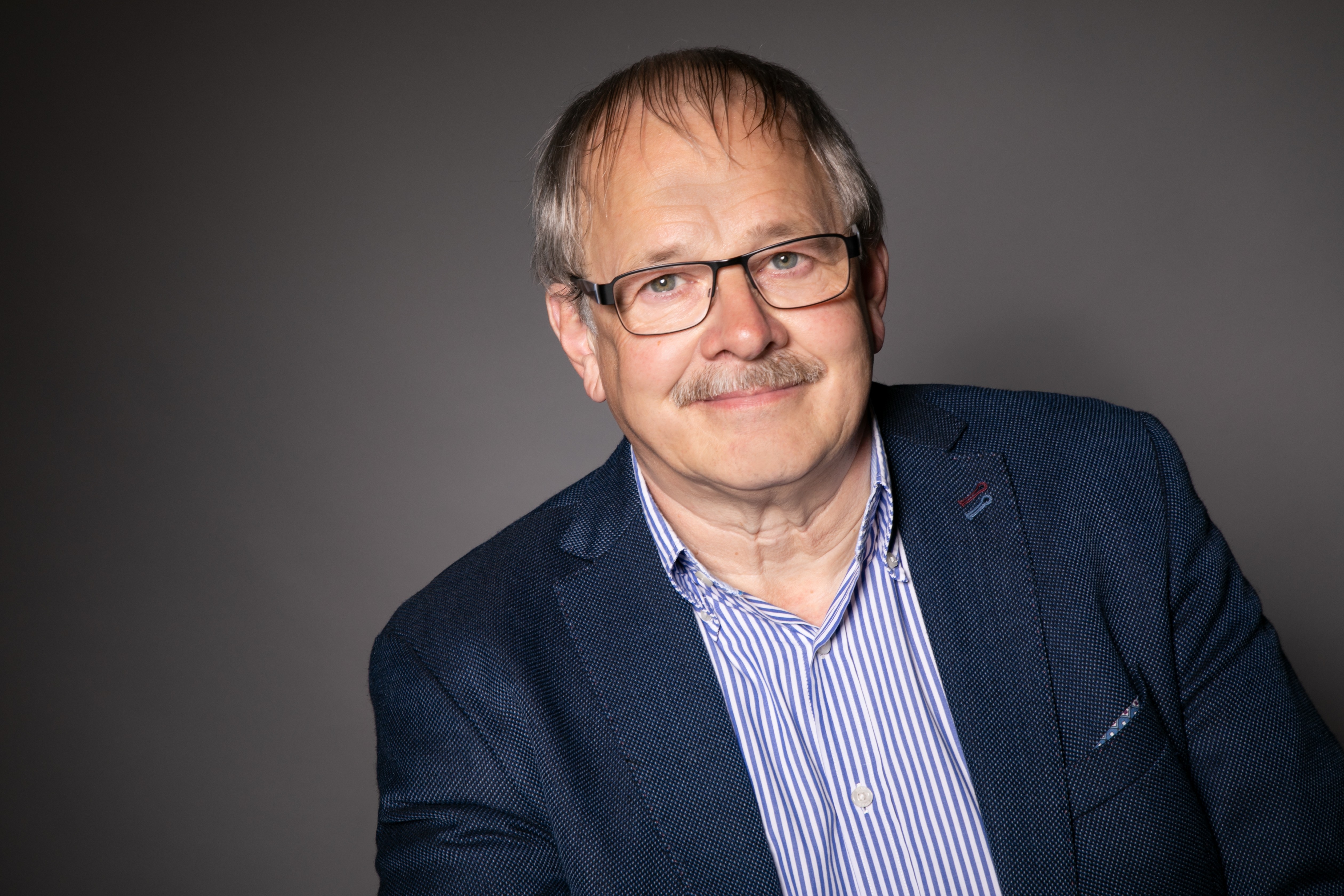 Porträtfoto von Christoph Eikenbusch, GEWOLean Mediator und Sparringpartner, mit Brille und Schnurrbart
